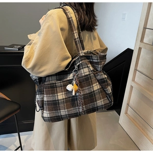 Detail of vintage wool plaid tote bag with charms shown in a lifestyle model shot
