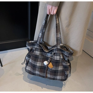 Detail of tartan wool tote bag with brand label and cute decorative charms