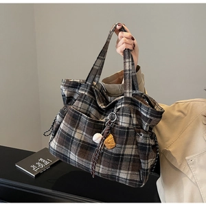 Detail of vintage plaid wool tote bag with baseball pendant charm for daily commute