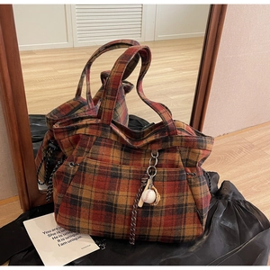Detail of red plaid tote bag featuring a creative baseball and glove charm attachment