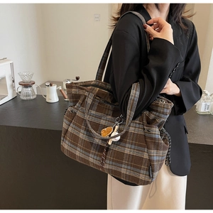 Detail of retro brown plaid tote bag with baseball charm and branding label