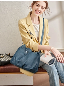Detail of navy blue pleated leather tote bag with silver buckle worn by a model