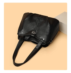 Detail of black large tote bag with distressed vintage texture and adjustable metal buckles