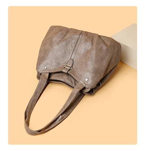 Detail of vintage brown leather tote bag with silver rivets and soft wrinkled texture