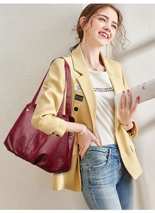 Close-up of a burgundy leather tote bag with a textured lychee grain and silver hardware