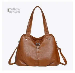 Detail view of yellow-brown leather tote bag with silver metal buckles and double handles