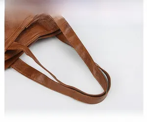 Detail of caramel brown tote handle featuring lychee texture and durable double stitching