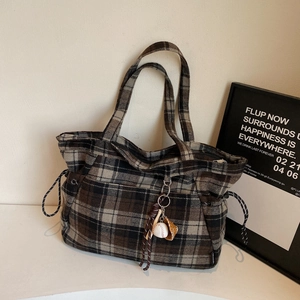 Retro plaid wool tote bag with baseball charm on minimalist light wall background