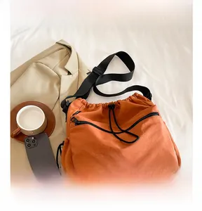 Close-up of caramel nylon bucket bag with drawstring closure and black zipper pocket