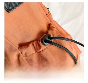 Detail view of the orange nylon bucket bag featuring a side pocket with black drawstrings