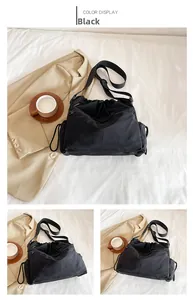 Detail of black nylon drawstring bucket bag with adjustable strap and utility pockets