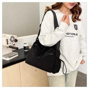 Detail of black nylon drawstring bucket bag showing zipper pockets and fashion logo