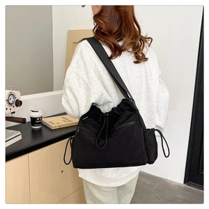 Detail view of large nylon drawstring bucket bag with side pockets and wide strap