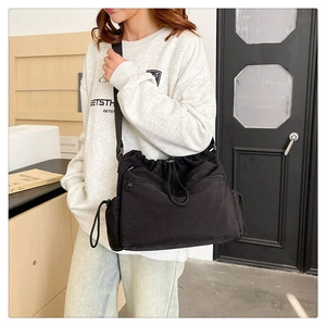Close-up of a large black nylon drawstring bucket bag with adjustable shoulder strap