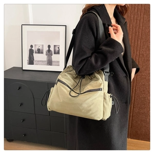 Detailed side view of khaki nylon bucket bag with dual zippers and adjustable shoulder strap