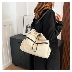 Detailed view of cream nylon bucket bag with adjustable black strap and front zipper
