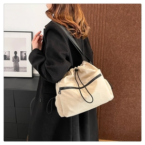 Detail of beige nylon drawstring bucket bag with black zipper pocket and sturdy fabric