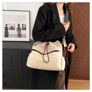 Detail of cream nylon bucket bag with black zip pocket and adjustable wide strap