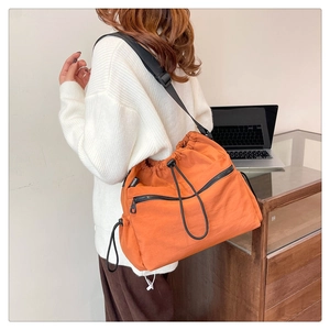 Close-up of bright orange nylon bucket bag featuring drawstring closure and fashion label
