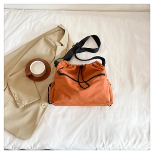 Detail of orange nylon bucket bag with adjustable drawstring and front zipper pocket