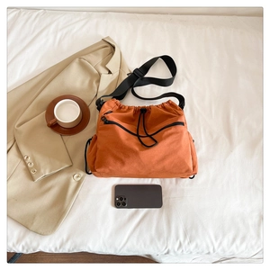 Detail of caramel nylon bucket bag with drawstring and pockets next to a coffee cup
