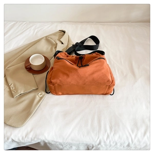 Detail of orange nylon drawstring bucket bag with zippered pockets and adjustable strap