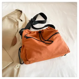 Detail of orange nylon bucket bag with drawstring closure and black front zipper pocket
