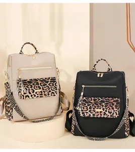Detail view of leopard print nylon backpacks with gold zippers and tassel accents