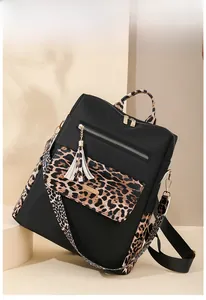 Detail view of anti-theft leopard print backpack featuring gold zippers and fringe tassel