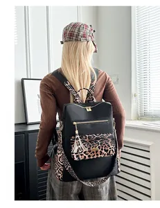 Detail view of stylish leopard print backpack with gold zippers and tassel charm