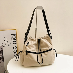 Minimalist beige nylon bucket bag with drawstring closure and adjustable shoulder strap