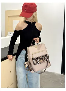 Detail view of large beige leopard print backpack with gold zipper and tassel charms
