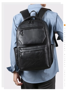 Detail view of the black PU leather backpack showing fine texture and zipper pockets
