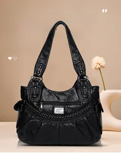 Detail of black pebbled leather texture on tote bag with V-shaped woven pattern and zip