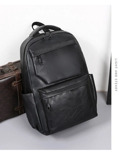 Detail view of black PU leather backpack with multi-pocket design on vintage suitcase