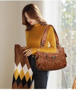 Detailed texture of brown vintage soft leather shoulder bag with woven decorative straps