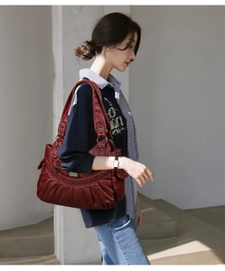 Detail of dark red washed leather shoulder bag with woven texture and retro rivets