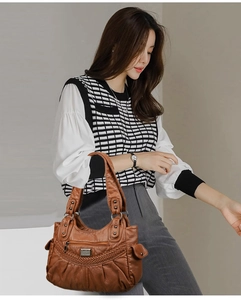 Close-up of brown soft leather shoulder bag with weave detail and multiple zip pockets