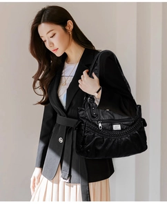 Detail view of the black washed leather shoulder bag with woven texture and logo plate