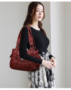 Detail of burgundy washed faux leather shoulder bag with woven texture and zippers