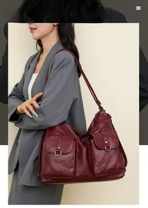 Detail of burgundy pebbled leather backpack showing functional front flap pockets and ring