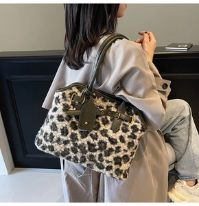Détail d'un sac cabas en peluche léopard avec bordures en cuir vert et boucles dorées