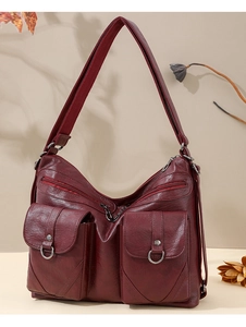 Detail of burgundy vintage faux leather tote with functional pockets and metal ring accents