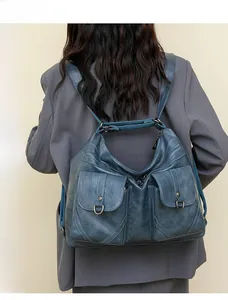 Retro teal faux leather backpack with multiple pockets shown on model wearing grey blazer