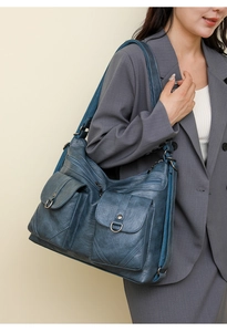 Blue soft leather shoulder bag with multi-pocket design on grey business suit