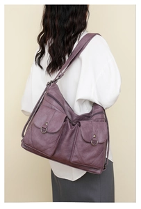 Detail of purple soft leather tote bag showing pocket texture and metallic buckle accents