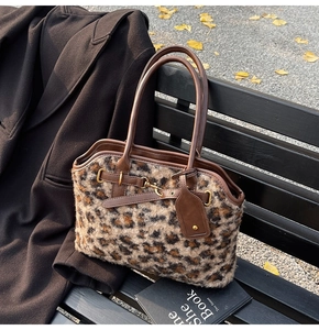 Détail d'un sac cabas en peluche léopard avec poignées en cuir marron sur un banc