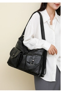 Detailed view of black faux leather tote with multiple functional zip pockets and D-rings