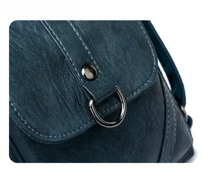 Macro detail of dark blue textured leather handbag featuring gunmetal snap button and D-ring