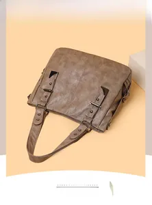 Detail of vintage brown leather tote featuring metallic rivets and wide shoulder strap